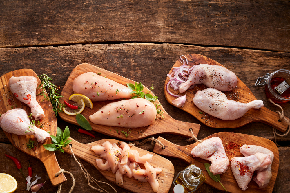 assorted cuts of chicken on cutting boards with seasonings