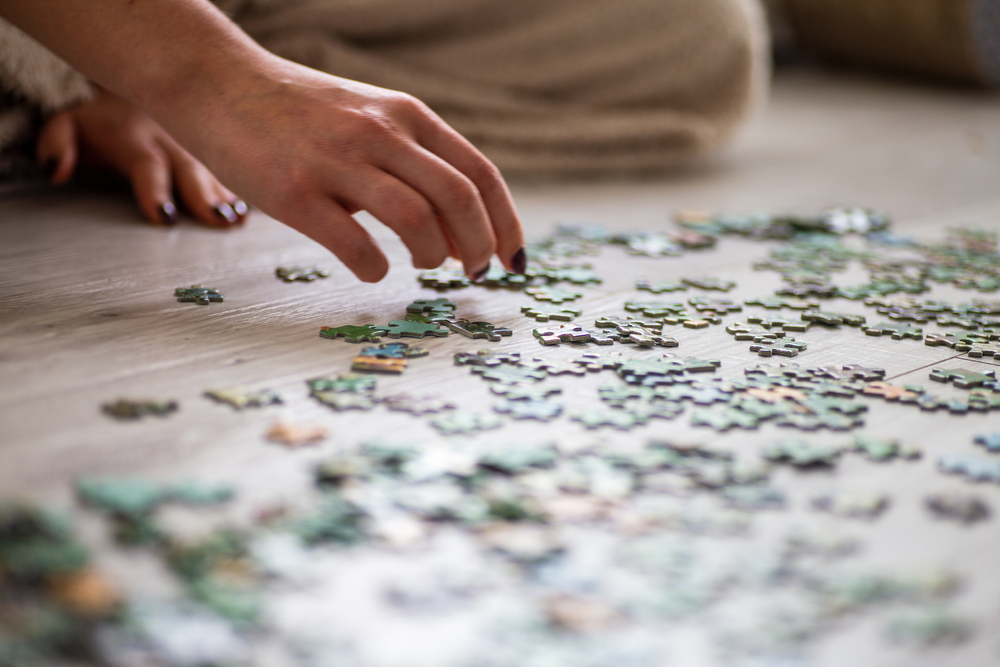 hand putting together jigsaw puzzle