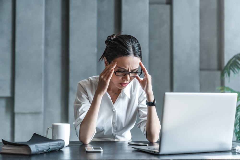 stressed woman holding head while working on laptop