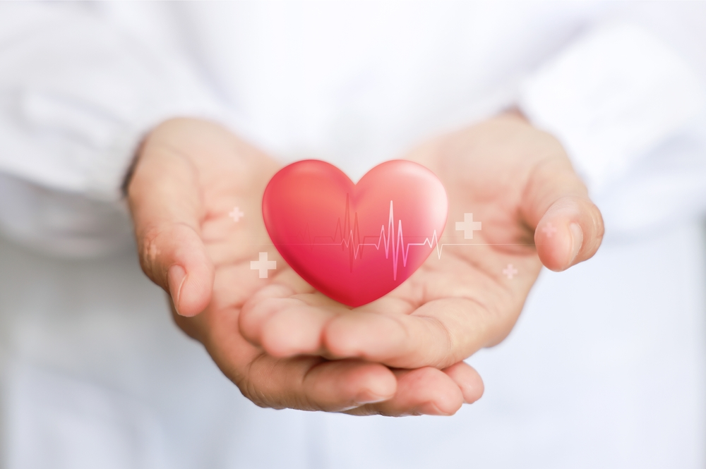 hands holding red heart shape overlaid with heart beat